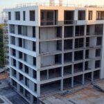 Canteiro de obras de núcleo jurídico da Defensoria Pública em São Sebastião, com estrutura em construção e vista para o mar.