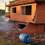 Residência em Ceilândia danificada por explosão de botijões de gás, com destroços e fumaça.