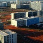 Vista panorâmica de Brasília com arquitetura moderna e áreas urbanas, representando licitação de 86 imóveis no Distrito Federal.