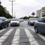 Via movimentada no Jardim Botânico, DF, com marcas de acidentes e demanda por passarela de pedestres.