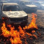 Incêndio em vegetação seca danificando oito carros em rua de Vicente Pires, DF, com chamas e fumaça.