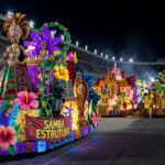 Avenida em Brasília com bandeiras brasileiras em desfile cívico, representando crítica da oposição a homenagem e ação na Justiça.