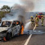 Carro Ford Fiesta pegando fogo na DF-001 perto do Jardim Botânico, com bombeiros controlando as chamas em Brasília.