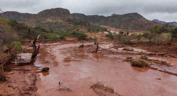 Paisagem devastada por tragédia ambiental na Zona da Mata Mineira, com florestas destruídas e rios transbordando.