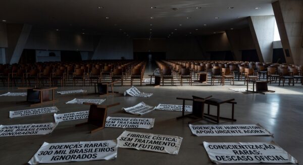 Fachada da CLDF em Brasília com banners de fitas zebra para o Dia das Doenças Raras, expondo falhas no apoio a pacientes.