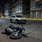 Cena de crime em rua de Taguatinga com moto caída e fita de isolamento policial.