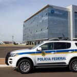 Viatura da Polícia Federal em frente ao prédio do BRB em Brasília, representando operação de prisão.