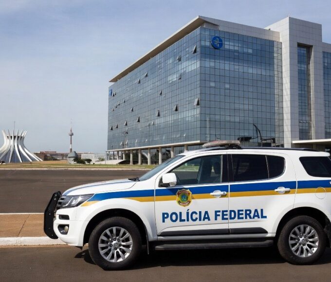 Viatura da Polícia Federal em frente ao prédio do BRB em Brasília, representando operação de prisão.