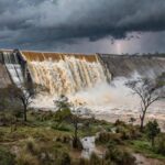 Barragem de Santa Maria transbordando no DF, expondo riscos de inundações após seca.