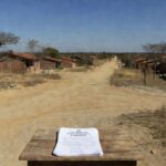 Paisagem de Planaltina com casas e documentos de regularização fundiária do GDF.