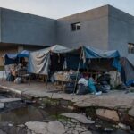 Rua urbana brasileira com barracas e pertences de pessoas em situação de rua